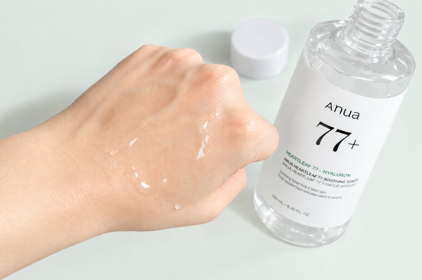 Anua Heartleaf 77 Soothing Toner poured onto the back of a hand beside the bottle